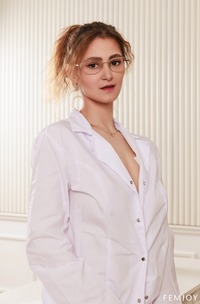 Lilliana Sits In An Office Chair Wearing A White Coat And Glasses